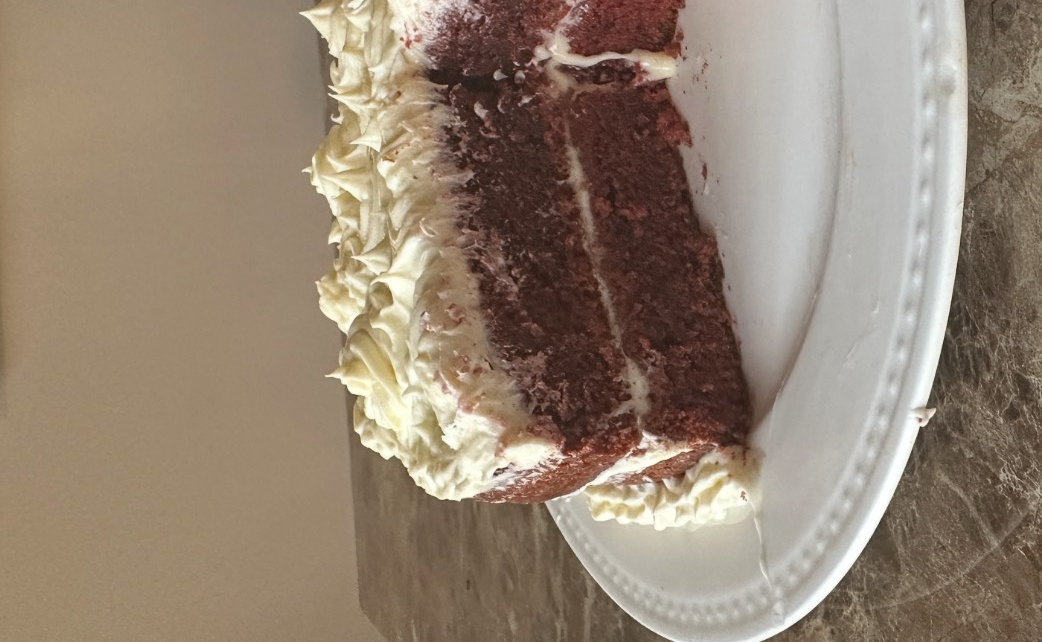 A photo of a two-tiered red velvet cake cut in half. It's decorated amateurishly.