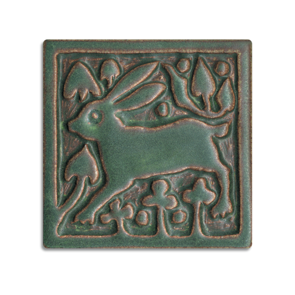 A deep green metal tile of a rabbit surrounded by stylized flora.