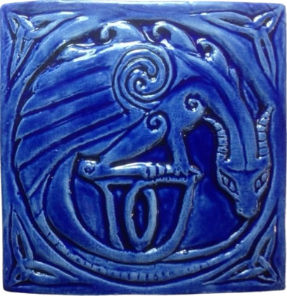 A blue ceramic tyle of a horned dragon sitting with its neck bowed so it forms a circle with its head and tail.