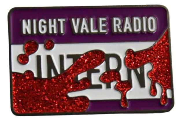 An enamel pin styled like a nametag. It reads, 'Night Vale Radio - Intern', and is spattered with glittery red blood.